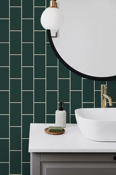 a white sink sitting under a round mirror next to a wall mounted faucet