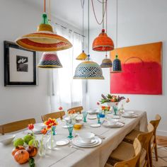 a dining room table with plates and bowls on it, hanging from the ceiling above