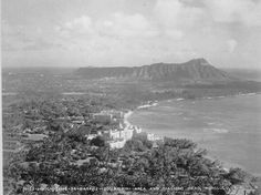 an aerial view of a city and the ocean with mountains in the backgroud