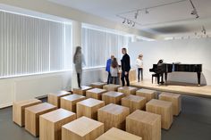 people are standing in an empty room with piano and stools on either side of the room