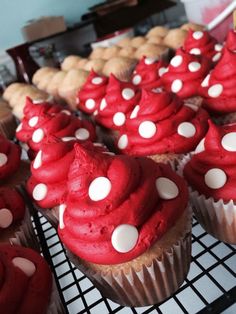 cupcakes with red frosting and white polka dots are on a cooling rack