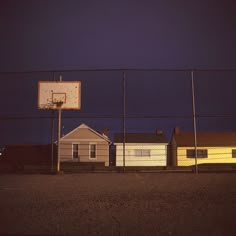 a basketball hoop in front of some houses at night