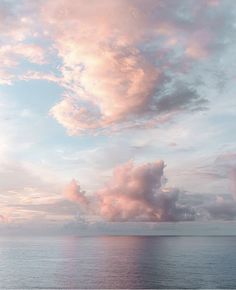 the sky is filled with pink clouds over the ocean