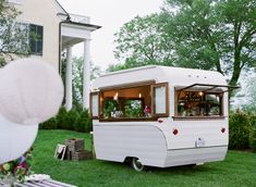 an old camper is parked on the grass in front of a large white house