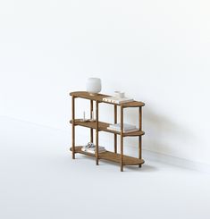 a small wooden shelf with two white vases sitting on it's sides, against a white wall