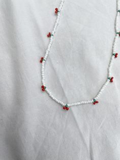 "A primarily white beaded necklace with beaded cherries.  Available in 4 different lengths: 12\" (30.5cm), 14\" (35.55cm), 16\" (40.65cm), 18\" (45.7cm), all adjustable with an extra 2.5\" of chain.  (Please see the final photo on this listing for examples of different lengths) Items are not waterproof, please keep them dry. I do not recommend showering or swimming in your Lula pieces.  Handmade in Tasmania, Australia We offer custom orders at Lula Handmade Jewellery! If you would prefer the necklace with silver or rose gold, or you would like the same style in a different colour, please send us a message and we would be happy to help.  PLEASE NOTE: All items are handmade, therefore no two items will be exactly the same. Your item may be slightly different to what is pictured in this listi Beads Necklace Outfit, Cherry Beaded Necklace, Beaded Cherry, Accesorios Aesthetic, White Beaded Necklace, Cherry Necklace, White Beaded Necklaces, Tasmania Australia, Summer Necklace