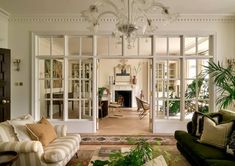 a living room filled with furniture and a chandelier hanging from the ceiling over a fire place