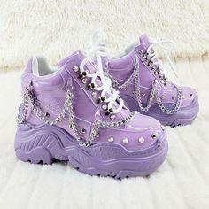 a pair of purple shoes with silver chains on them sitting on top of a white blanket