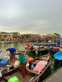 several people are standing on small boats docked in the water with umbrellas around them