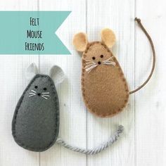 two felt mouses sitting next to each other on top of a white wooden surface