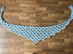 a blue crocheted shawl on a wooden floor