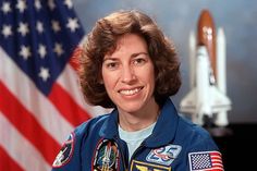 a woman in an astronaut's uniform next to the american flag and a space shuttle