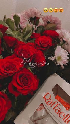 a bouquet of red roses sitting next to a box of chocolates and some flowers