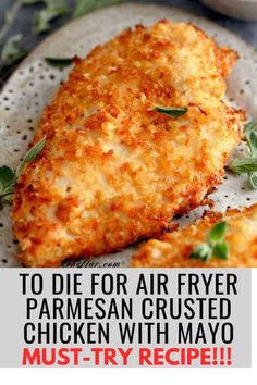 two pieces of fried parmesan crusted chicken on a white plate with herbs