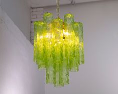 a green chandelier hanging from the ceiling in a room with white walls and flooring