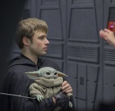 a man holding a baby yoda in his arms