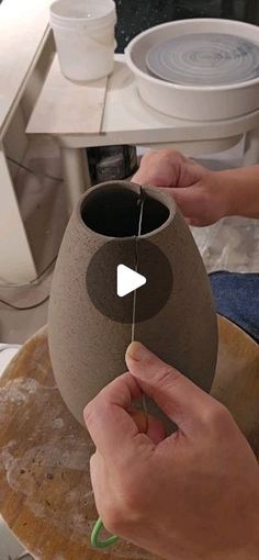 a person is making a vase out of clay