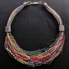 a multicolored necklace is displayed on a black surface, with metal clasps