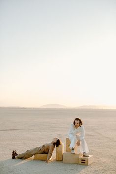 two people laying on blocks in the desert