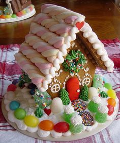 a decorated gingerbread house with candy and candies on a tablecloth covered table