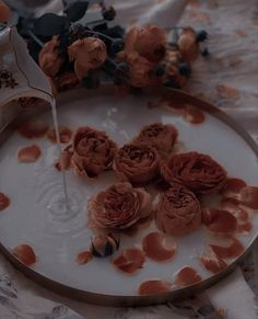 a plate with some flowers on it and water pouring from a faucet in the middle