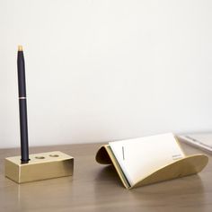 a pen sitting on top of a wooden desk next to a notepad and pencil holder