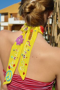 the back of a woman wearing a yellow scarf with peace on it