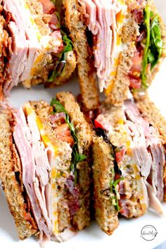 several sandwiches stacked on top of each other with meat and veggies in them