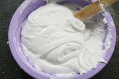 a purple bowl filled with white icing on top of a counter