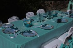 the table is set with plates and silverware for an elegant teal color scheme