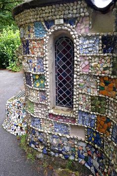 a building made out of rocks with a window in the middle and lots of glass on it