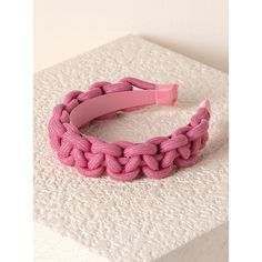 a pink braided bracelet sitting on top of a white surface with a rubber band