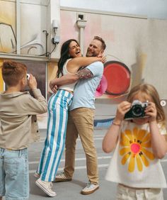 a man and woman hug each other while taking pictures with children in front of a food truck