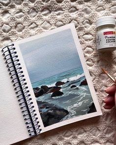 a person holding a pen and writing on a notebook next to an open photo album