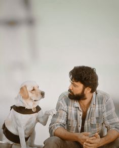 a man sitting on the ground next to a dog