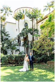 a bride and groom standing in front of a building with palm trees on the lawn