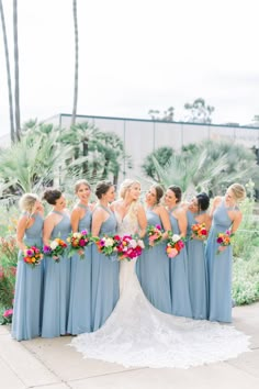 a bride and her bridesmaids pose for a photo in front of palm trees