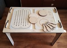 a white tray with utensils and plates on it sitting on a wooden floor