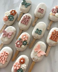 there are many decorated ice creams on the sticks with flowers and butterflies in them