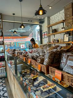 a woman standing in front of a bakery counter filled with pastries and desserts