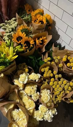 a bunch of sunflowers and other flowers sitting on the ground next to each other