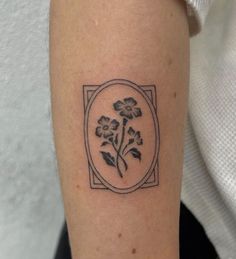 a black and white photo of a flower tattoo on the right arm with an oval frame around it