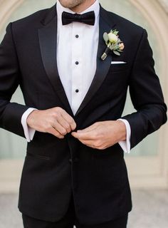 a man wearing a black tuxedo with a flower in his lapel