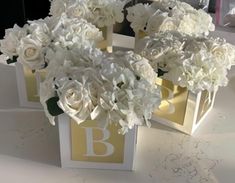 two boxes with flowers in them sitting on a table next to each other and the letter b