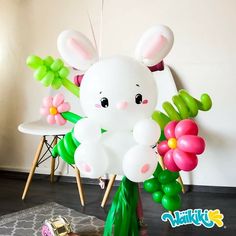 an air filled balloon bunny sitting on top of a table with flowers and balloons attached to it