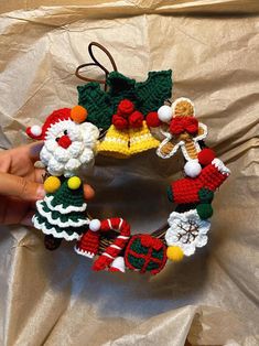 a hand holding a christmas wreath ornament made out of crocheted yarn