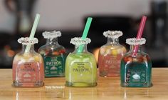 four small bottles with straws in them sitting on a table