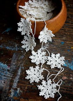 some white crocheted flowers in a wooden bowl