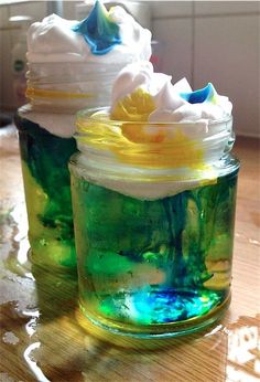 two jars filled with whipped cream on top of a wooden table