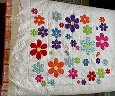 a white quilt with multicolored flowers on it